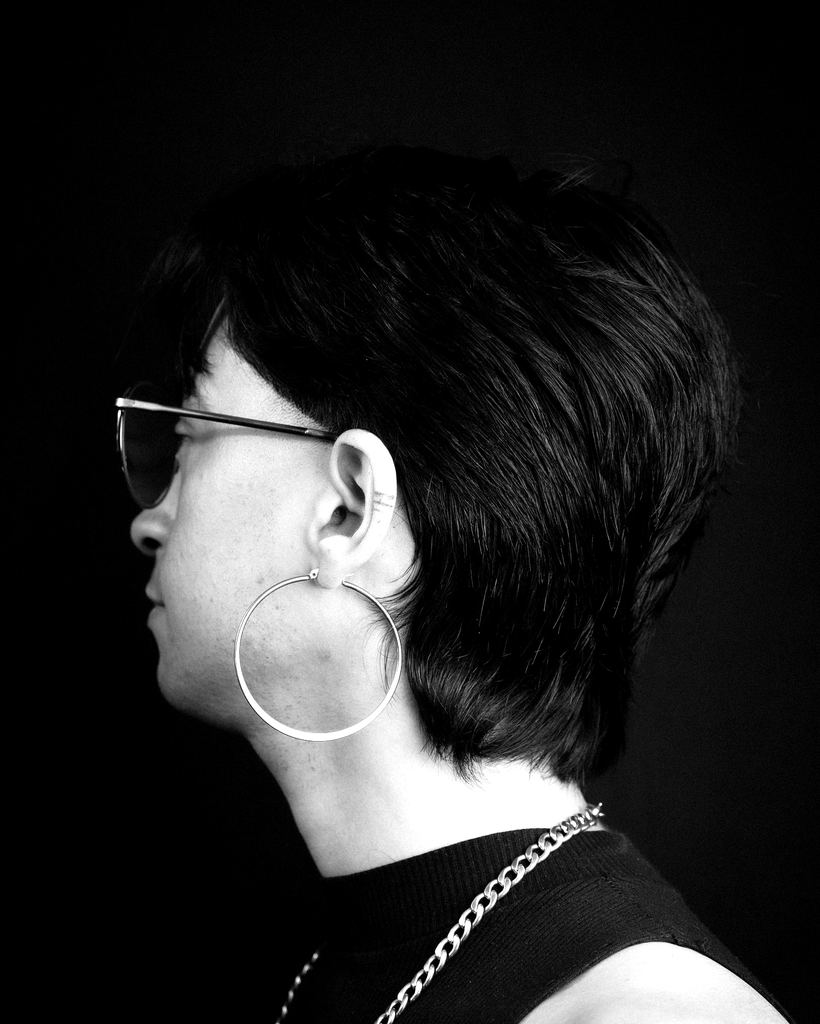 Perfil de un cliente con mullet y lentes, fondo negro